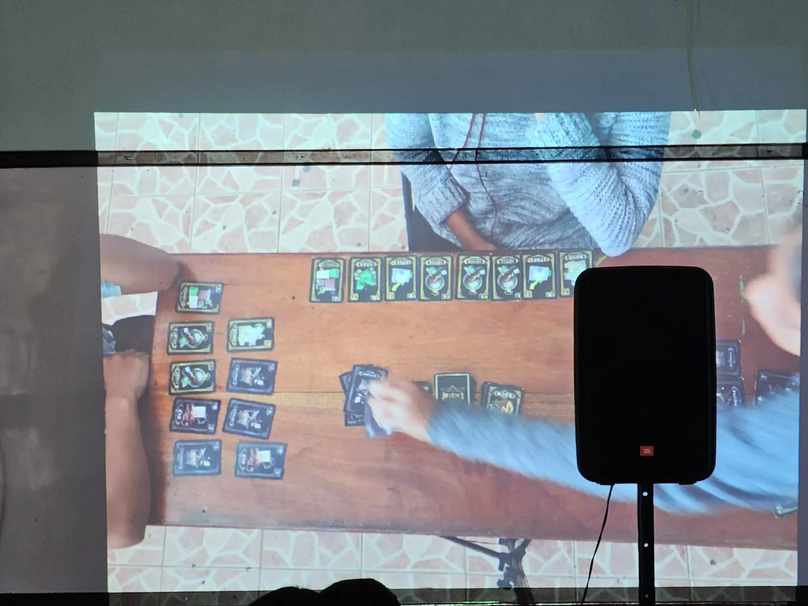 Get Rich! card game demonstration projected during a student assembly
